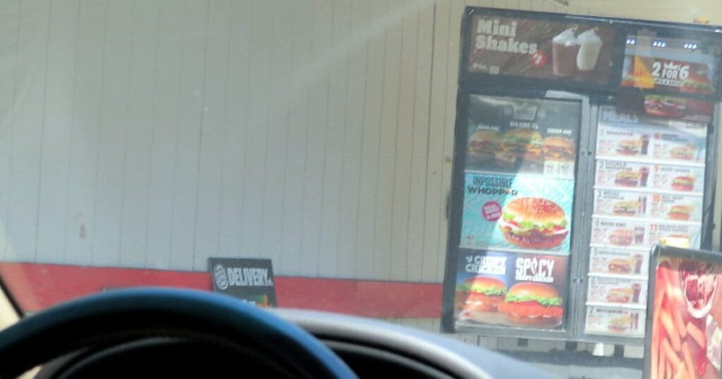 View of a fast-food drive-thru menu board with burgers and shakes.