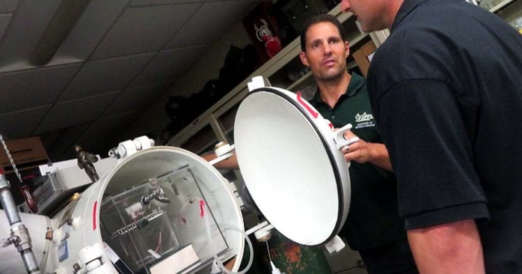 Two men discussing a large scientific apparatus in a lab setting.